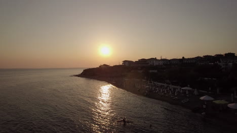 Luftaufnahme-Des-Resorts-Und-Des-Meeres-Bei-Sonnenuntergang-Am-Strand-Von-Trikorfo,-Griechenland