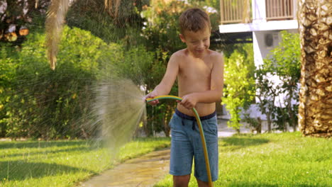 Kind-Bewässert-Rasen-Mit-Schlauch