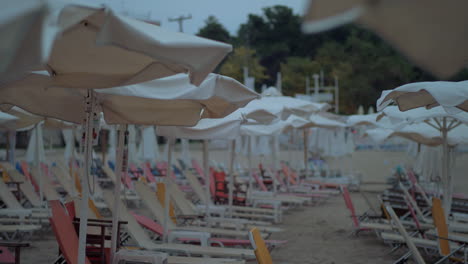 Empty-sunbeds-under-umbrellas-on-resort-in-windy-evening