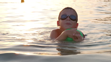 Junge-Mit-Ball-Schwimmt-Bei-Sonnenuntergang-Im-Meer
