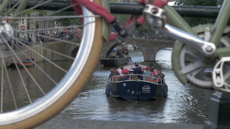 View-from-the-bridge-of-moving-on-the-canal-boat-with-people-Amsterdam-Netherlands