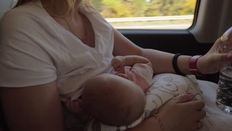 Mother-breastfeeding-baby-and-drinking-water-in-the-car