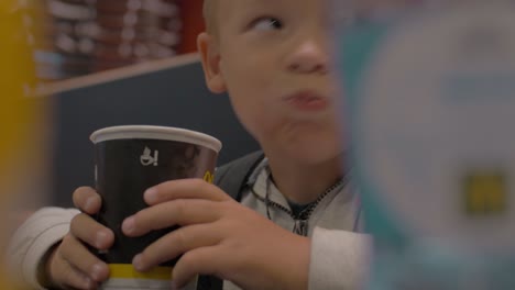 View-of-small-boy-drinking-from-the-paper-cup-and-smiling-fast-food-cafe