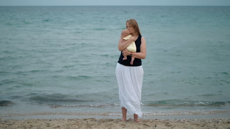 Mother-cuddling-baby-scene-at-the-beach-against-the-sea