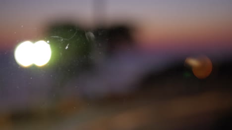 Blurred-cars-driving-with-headlights-on-Evening-view-through-the-glass