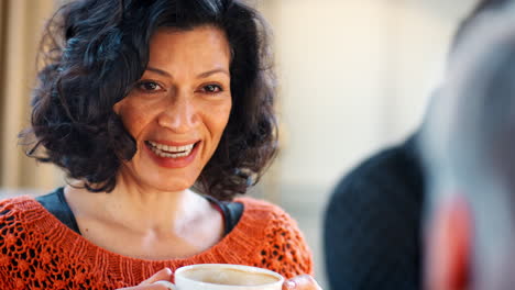 Middle-Aged-Woman-Meeting-Friends-Around-Table-In-Coffee-Shop