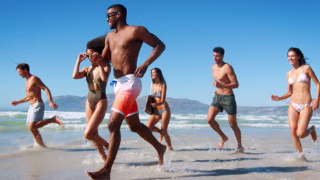Group-Of-Friends-Running-Through-Waves-On-Beach-Vacation