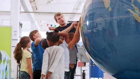 School-kids-using-giant-globe-with-teacher-at-science-centre