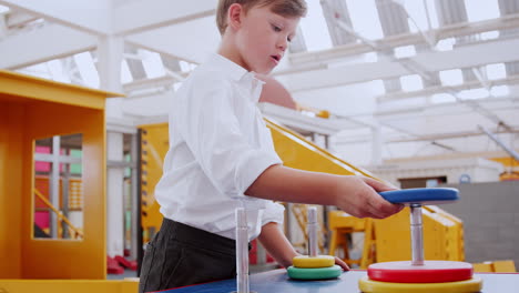 Young-white-boy-building-ring-tower-puzzle-at-science-centre