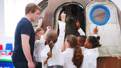 Kids-and-teacher-looking-at-space-capsule-in-science-centre