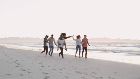 Group-Of-Friends-Having-Fun-Running-Along-Winter-Beach-Together