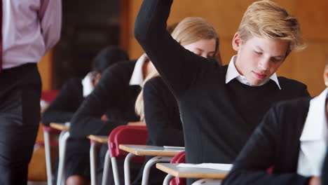 Teenage-Student-Sitting-Examination-Asking-Teacher-Question
