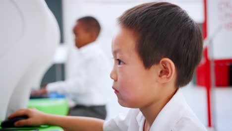 Asian-schoolboy-using-computer-at-a-science-centre,-close-up