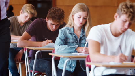 Teenager-Studenten-Sitzen-In-Der-Prüfung,-Während-Der-Lehrer-Sie-Beaufsichtigt