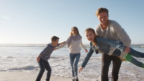 Family-On-Winter-Beach-Running-Away-From-Advancing-Waves