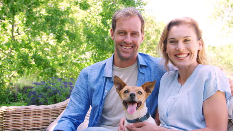 Happy-white-couple-sitting-in-the-garden-with-their-pet-dog