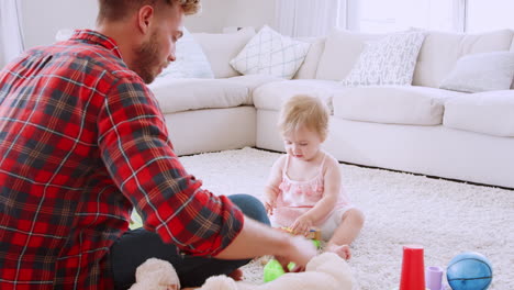 Dad-and-toddler-daughter-playing-instruments-in-sitting-room