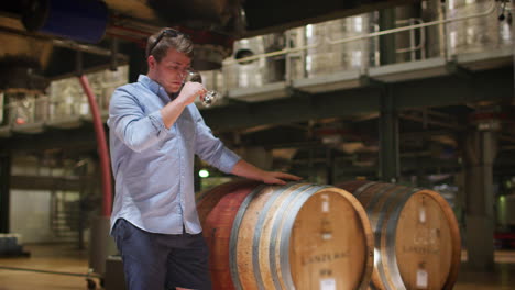 Young-man-wine-tasting-in-a-wine-factory-warehouse