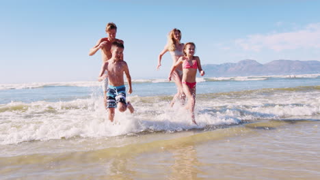 Parents-and-Children-In-Swimsuits-Running-Out-Of-Sea-On-Summer-Vacation