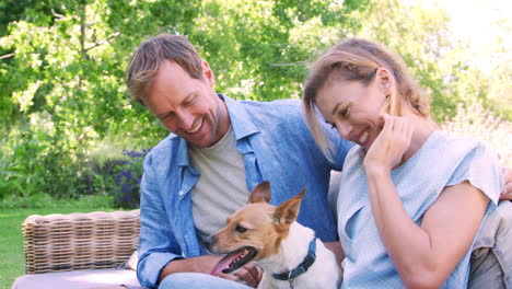 Happy-white-couple-sit-petting-their-dog-in-the-garden