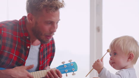 Dad-and-toddler-son-play-with-instruments-at-home,-close-up