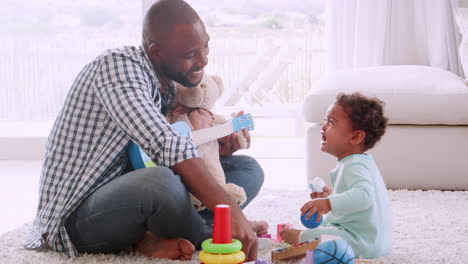 Young-black-father-singing-to-his-crying-son-in-sitting-room