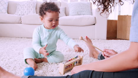 Black-toddler-playing-xylophone-with-his-mum-in-sitting-room