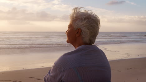 Rückansicht-Einer-älteren-Frau-Am-Strand,-Die-Den-Sonnenuntergang-über-Dem-Meer-Beobachtet