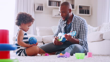 Young-black-dad-playing-with-young-daughter-in-sitting-room