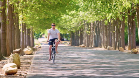 Junger-Weißer-Mann-Fährt-Fahrrad-Auf-Einer-Von-Bäumen-Gesäumten-Straße