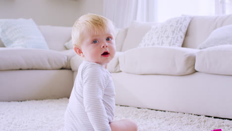 White-toddler-boy-crawls-and-sits-in-sitting-room,-close-up