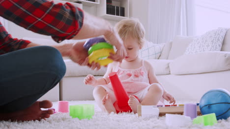 Young-dad-playing-with-toddler-daughter-at-home,-low-angle