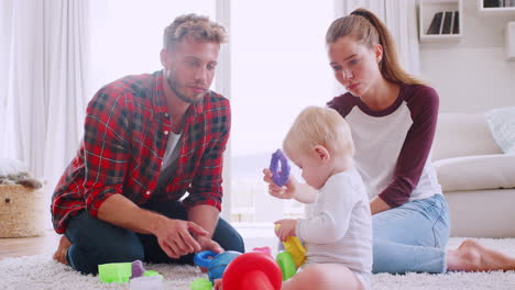 Young-couple-playing-with-their-toddler-on-the-floor-at-home