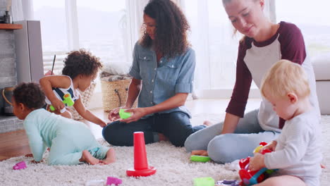 Schwarz-weiße-Frauen-Spielen-Mit-Kleinkindern-Auf-Dem-Boden