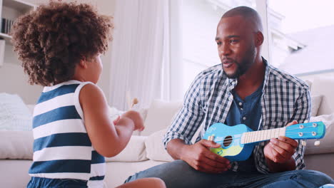 Young-black-dad-singing-and-playing-ukulele-with-daughter
