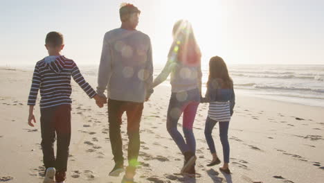 Rear-View-Of-Family-Walking-On-Winter-Beach-Holding-Hands