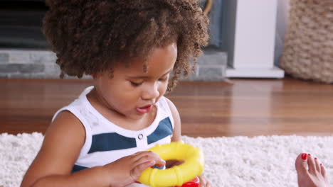 Young-black-girl-playing-with-plastic-rings-in-sitting-room