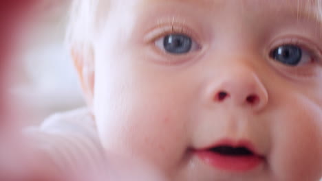 White-toddler-boy-making-face,-reaching-to-camera,-close-up
