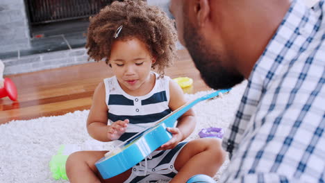 Young-black-girl-playing-ukulele-and-singing-with-her-dad