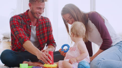 Young-couple-sitting-on-floor-playing-with-toddler-daughter