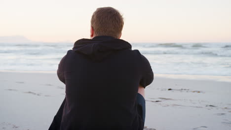 Rückansicht-Eines-Jungen-Mannes-Am-Strand,-Der-Den-Sonnenaufgang-über-Dem-Meer-Beobachtet