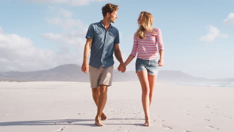 Loving-Couple-On-Summer-Vacation-Walking-Along-Beach-Together