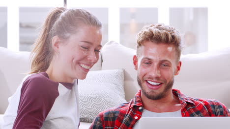 Young-couple-at-home-talking-and-using-laptop,-close-up