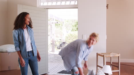 Female-Friends-Carrying-Boxes-Into-New-Home-And-Celebrating-On-Moving-Day