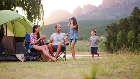 Kids-run-to-join-parents-sitting-by-tent-in-rural-setting