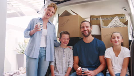 Portrait-Of-Family-Sitting-In-Back-Of-Removal-Truck-On-Moving-Day