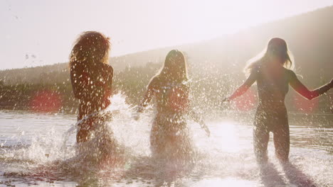 Three-female-friends-running-and-splashing-in-a-lake