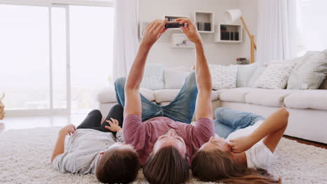 Father-And-Children-Lying-On-Rug-And-Posing-For-Selfie-At-Home