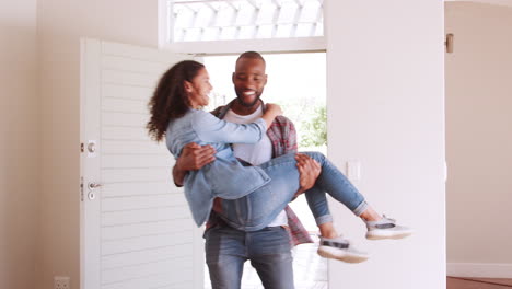 Man-Carrying-Woman-Over-Threshold-Of-Doorway-In-New-Home