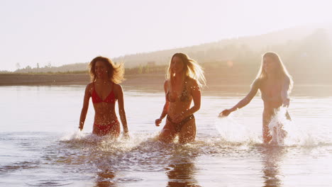Three-female-friends-running-and-splashing-in-a-lake